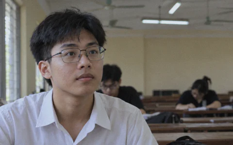 Sinh viên đeo kính cận gọng kim loại mảnh ngồi trong phòng tự học